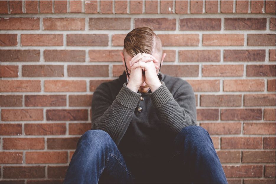 Мъж в депресия, облегнат на стена