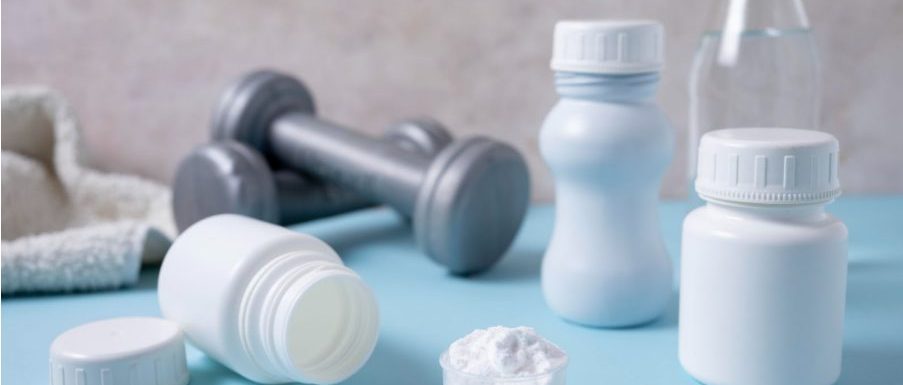 Дъмбели за тренировка и малки контейнери с Л-карнитин.