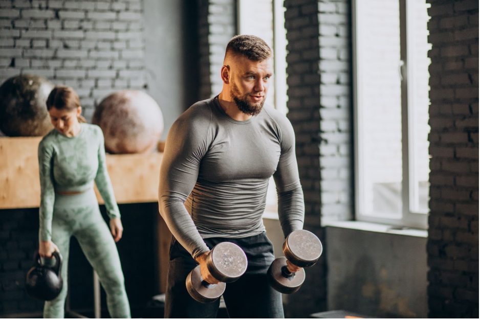 Мъж и жена, които тренират с тежести във фитнес зала