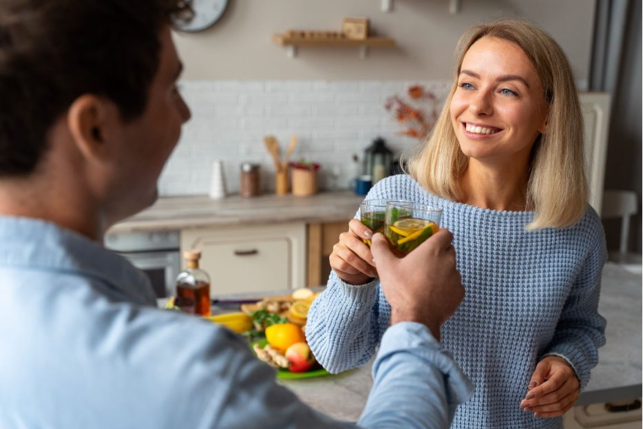 Мъж и жена, които се усмихват и вдигат чаши със здравословна напитка